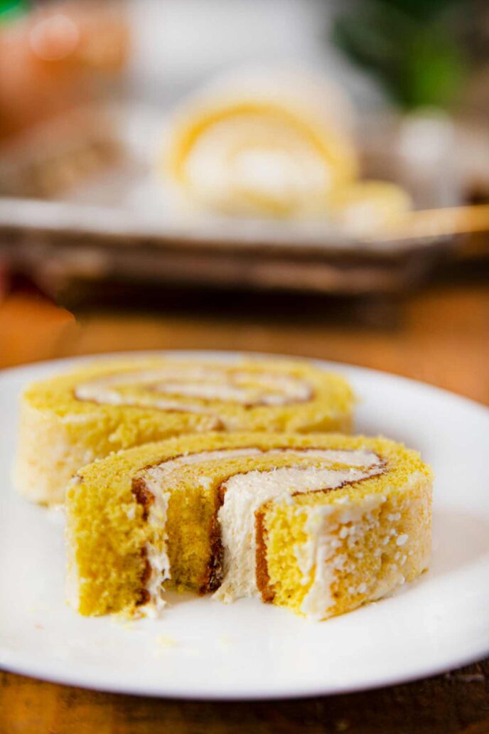 Bite out of slice of lemon cake roll on white plate