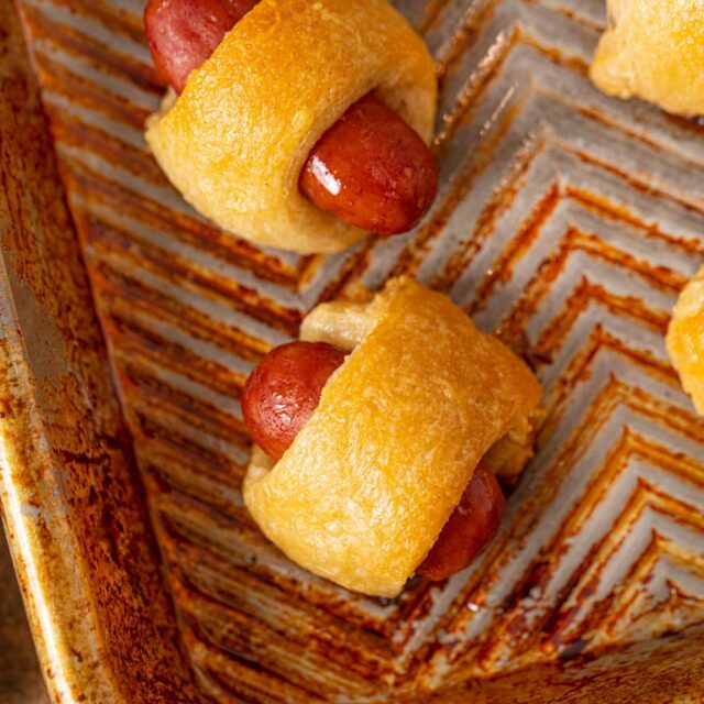 Mini Beef Smokie Wrapped in crescent dough to make a pig in a blanket on a metal tray