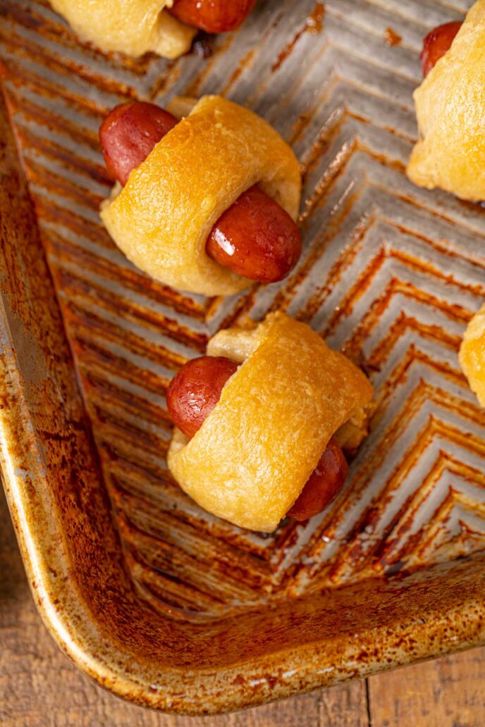 Mini Beef Smokie Wrapped in crescent dough to make a pig in a blanket on a metal tray