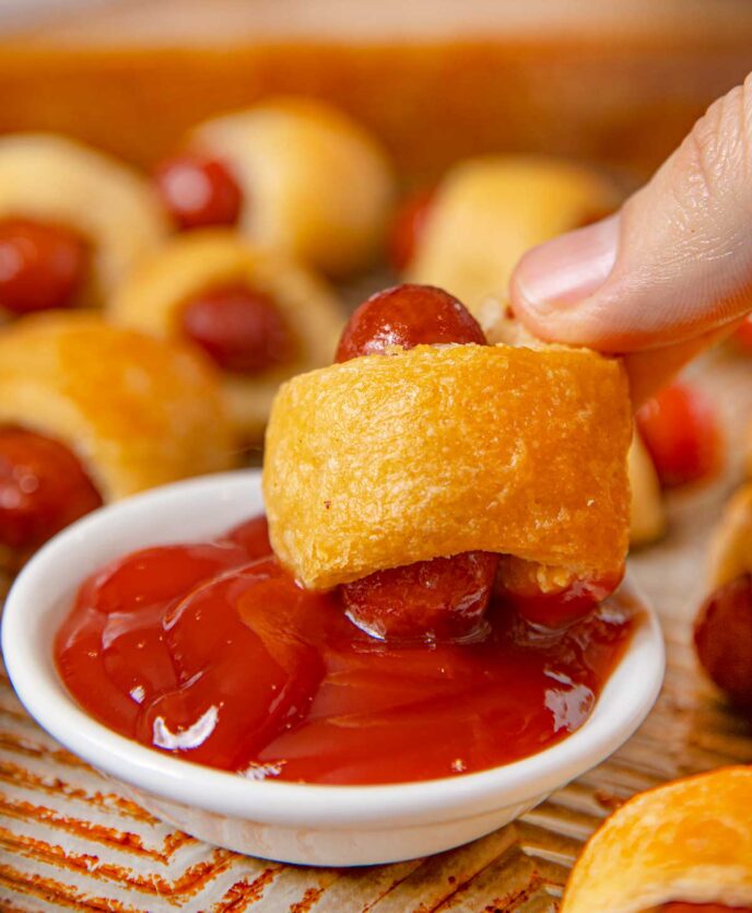 A Pig in a Blanket being dipped into ketchup