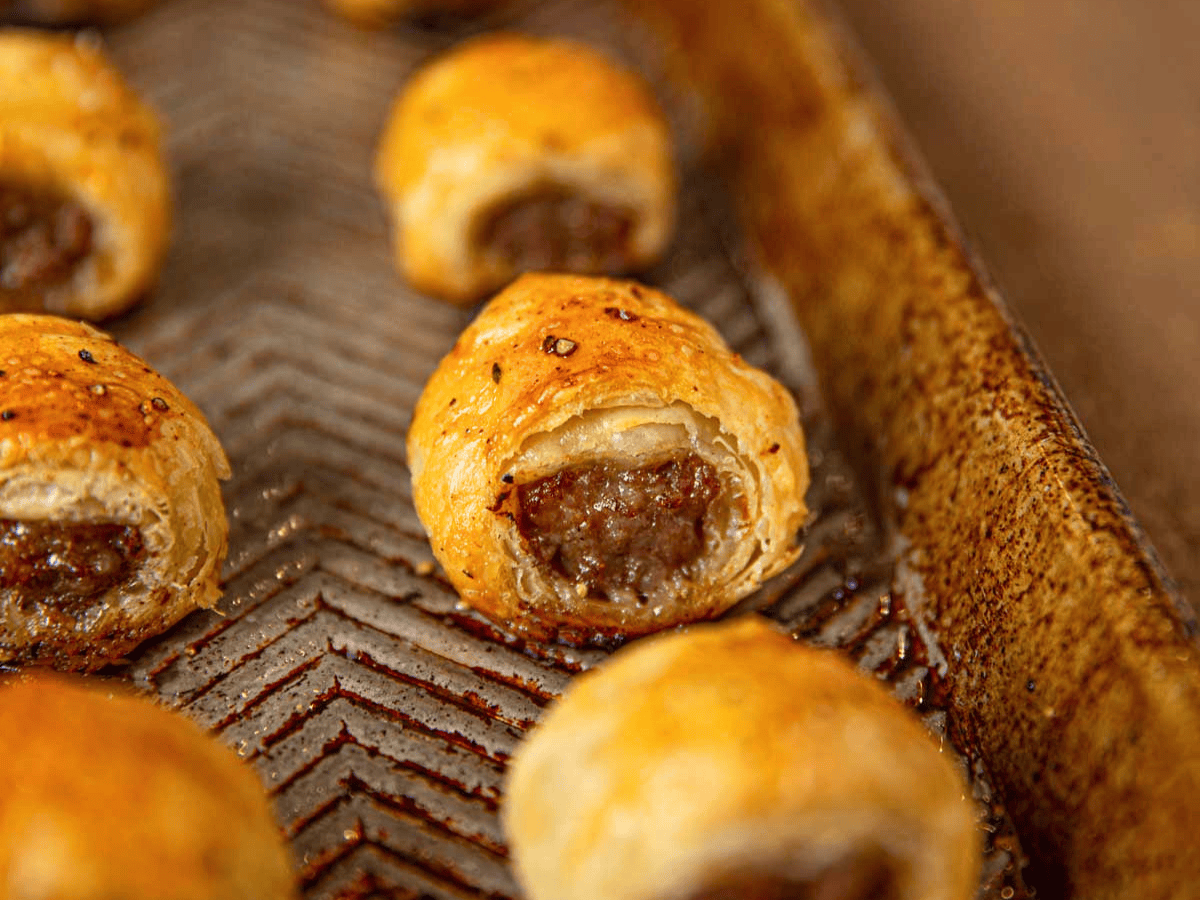 cooked pork wrapped in pastry on baking sheet in a line