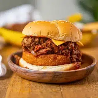 Assembled loaded ground beef sandwich on a wooden plate