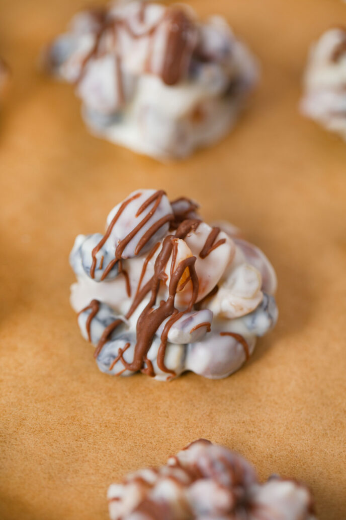 White Chocolate Fruit and Nut Clusters on baking sheet with chocolate drizzle