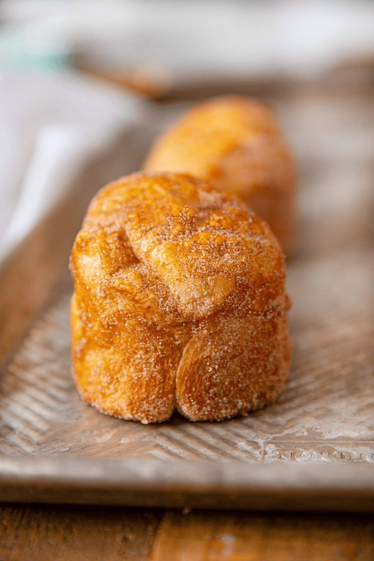 Croissant muffins covered in cinnamon sugar on a baking sheet