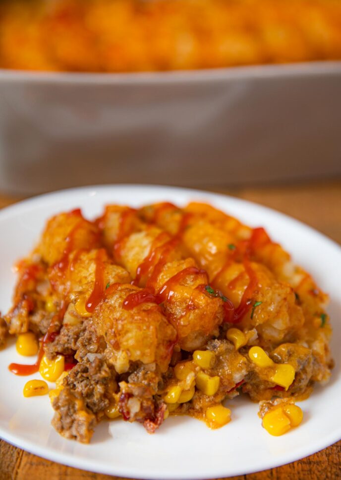 Square of Beefy Cowboy Casserole on white plate with ketchup on top