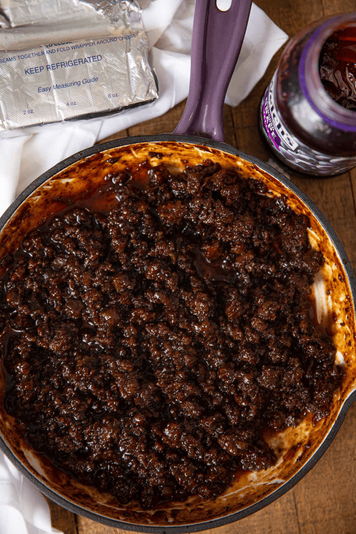 Ground meat in a pan with a jar of jelly on the side