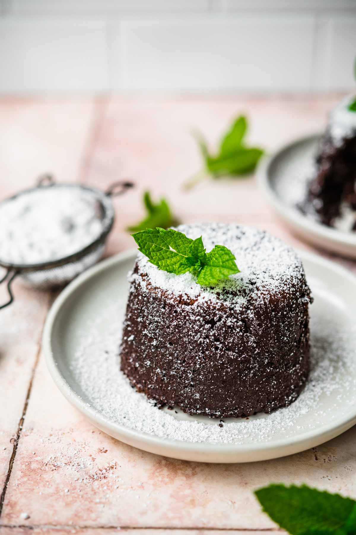 Molten Chocolate Cake on plate dusted with powdered sugar and garnished with mint leaves