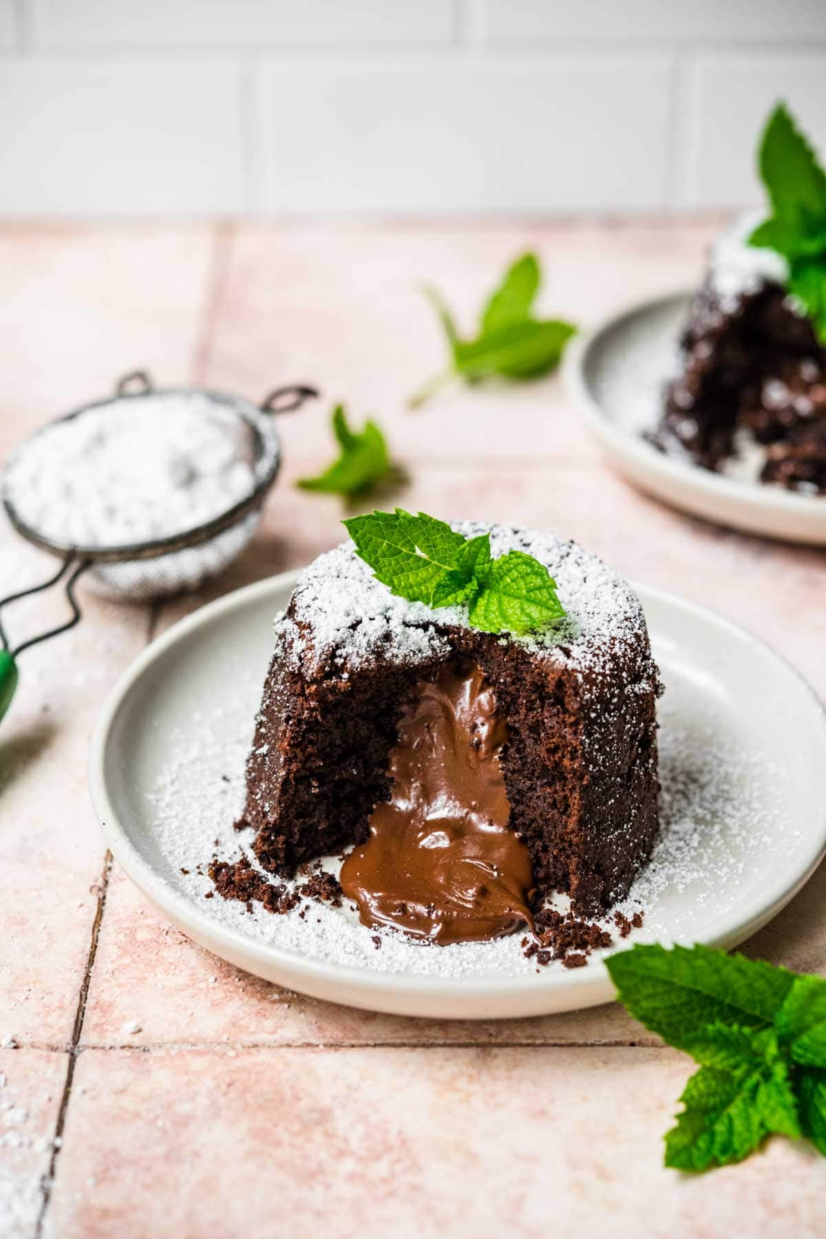 Molten Chocolate Cake on plate dusted with powdered sugar and garnished with mint leaves and melted center