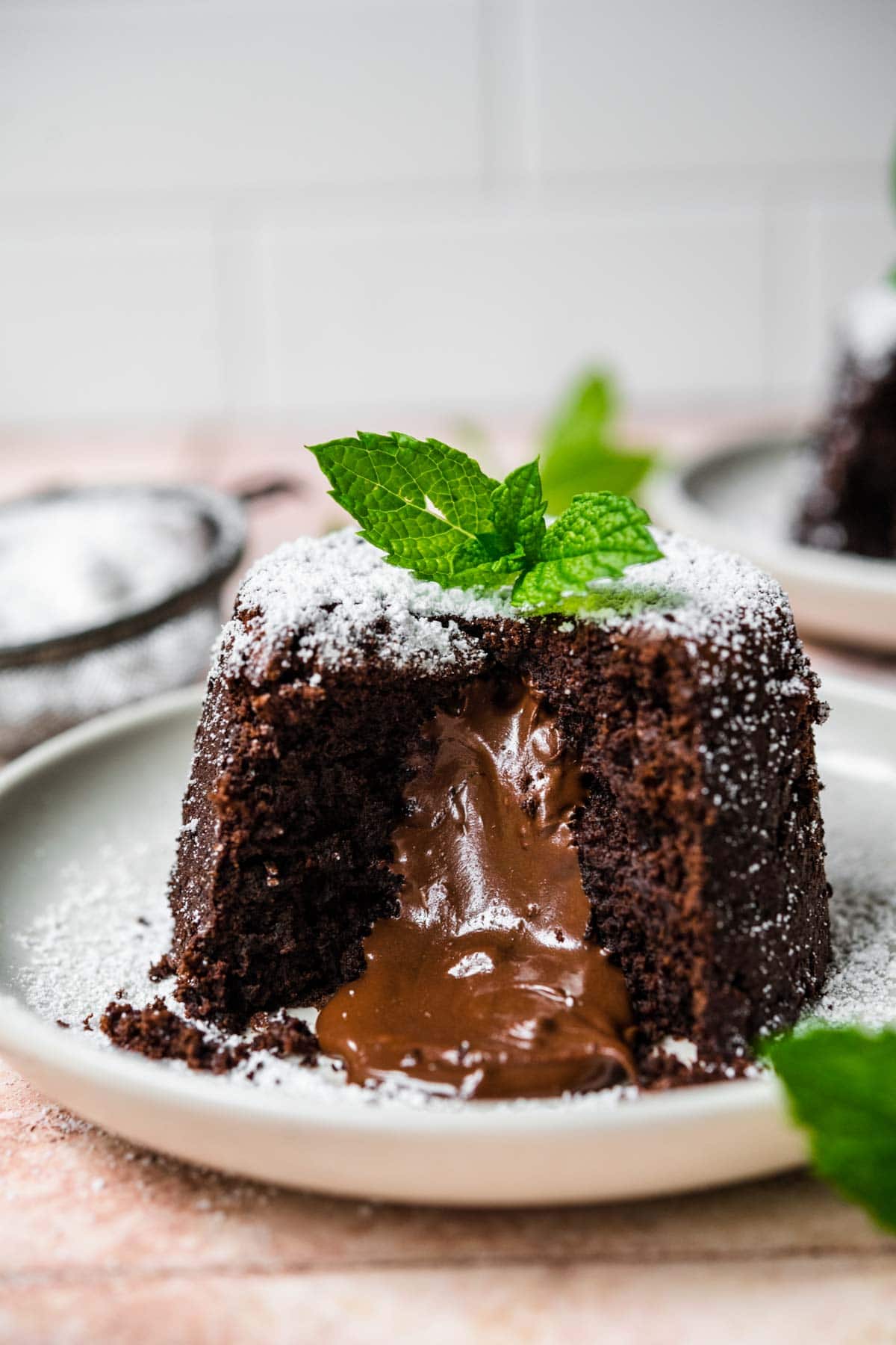 Molten Chocolate Cake on plate dusted with powdered sugar and garnished with mint leaves and melted center
