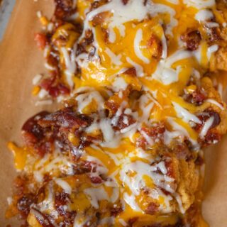 Chicken with melted cheese and toppings on baking sheet