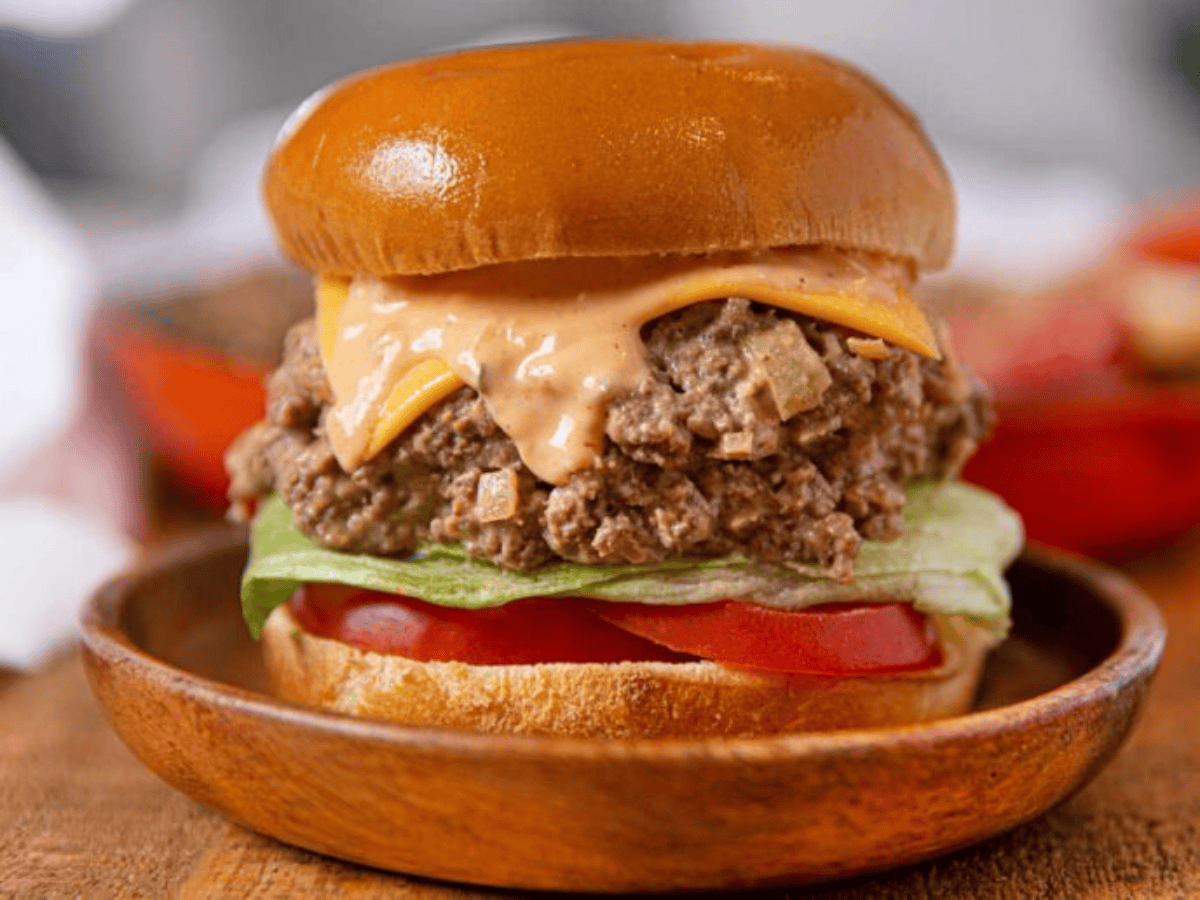Bun filled with meat with toppings on a wooden plate 