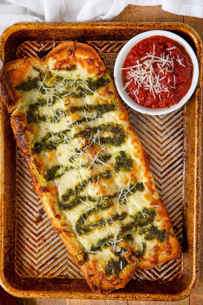 Pesto Cheesy Bread on baking sheet with dipping sauce