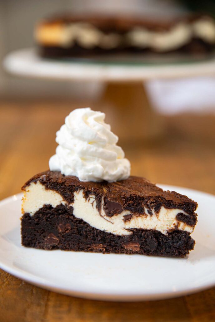 Brownie Cheesecake slice on plate with whipped cream