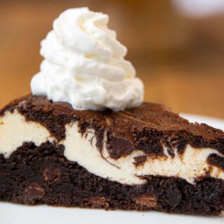 Brownie Cheesecake slice on plate with whipped cream