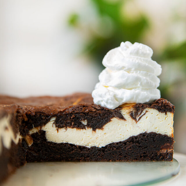 Brownie Cheesecake sliced open with whipped cream