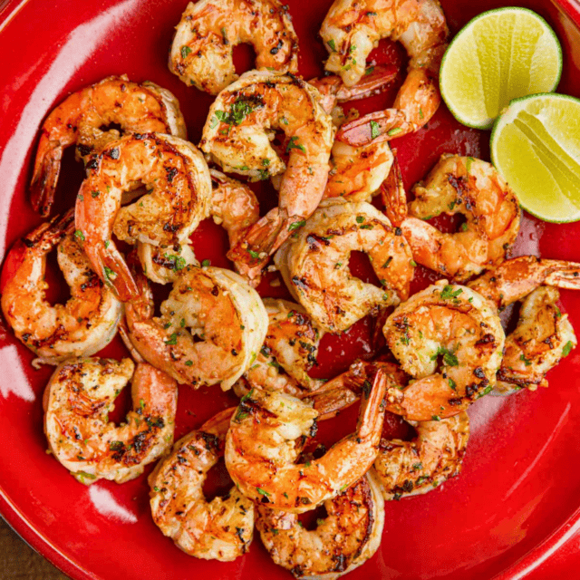 plate full of cooked citrus prawns with a citrus cut in half