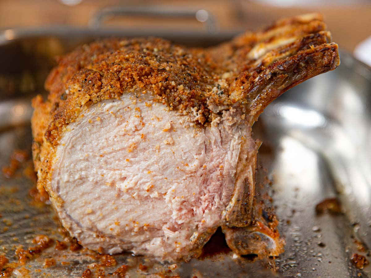 Herb Crusted Pork Rib Roast sliced in roasting pan