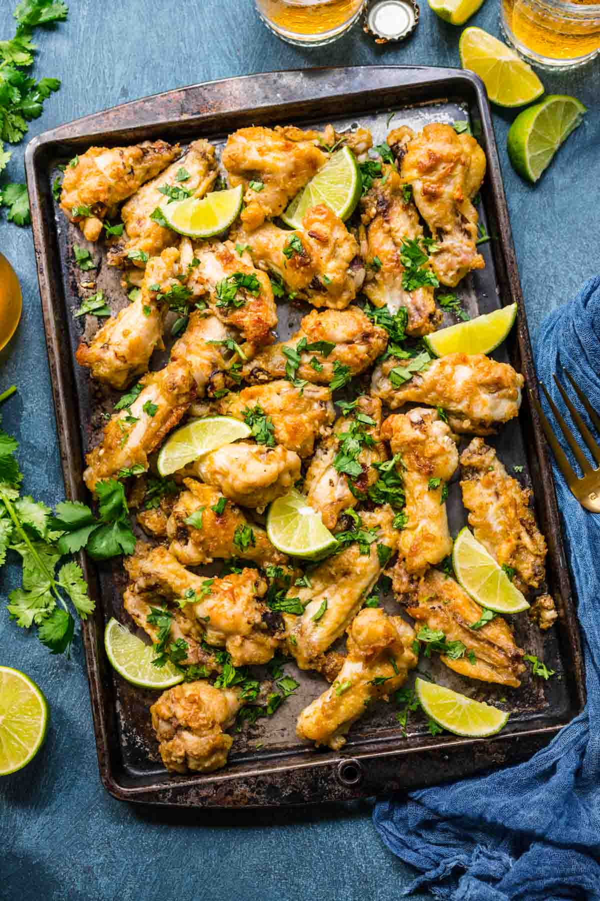 Thai Curry Chicken Wings baked on baking pan with cilantro and lime wedge garnish