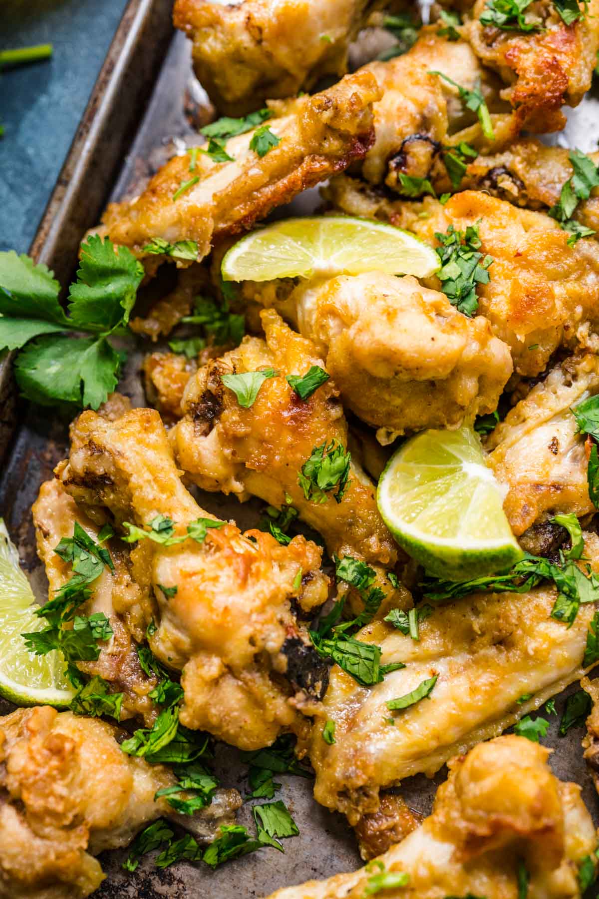 Thai Curry Chicken Wings baked on baking pan with cilantro and lime wedge garnish