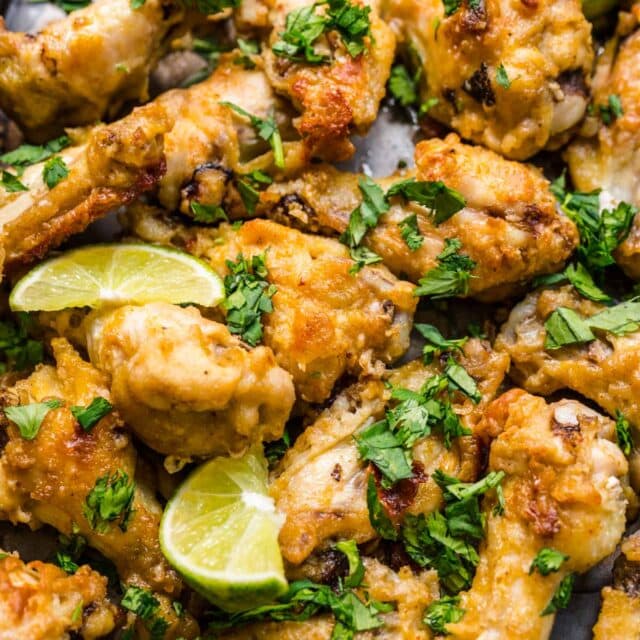 Thai Curry Chicken Wings baked on baking pan with cilantro and lime wedge garnish