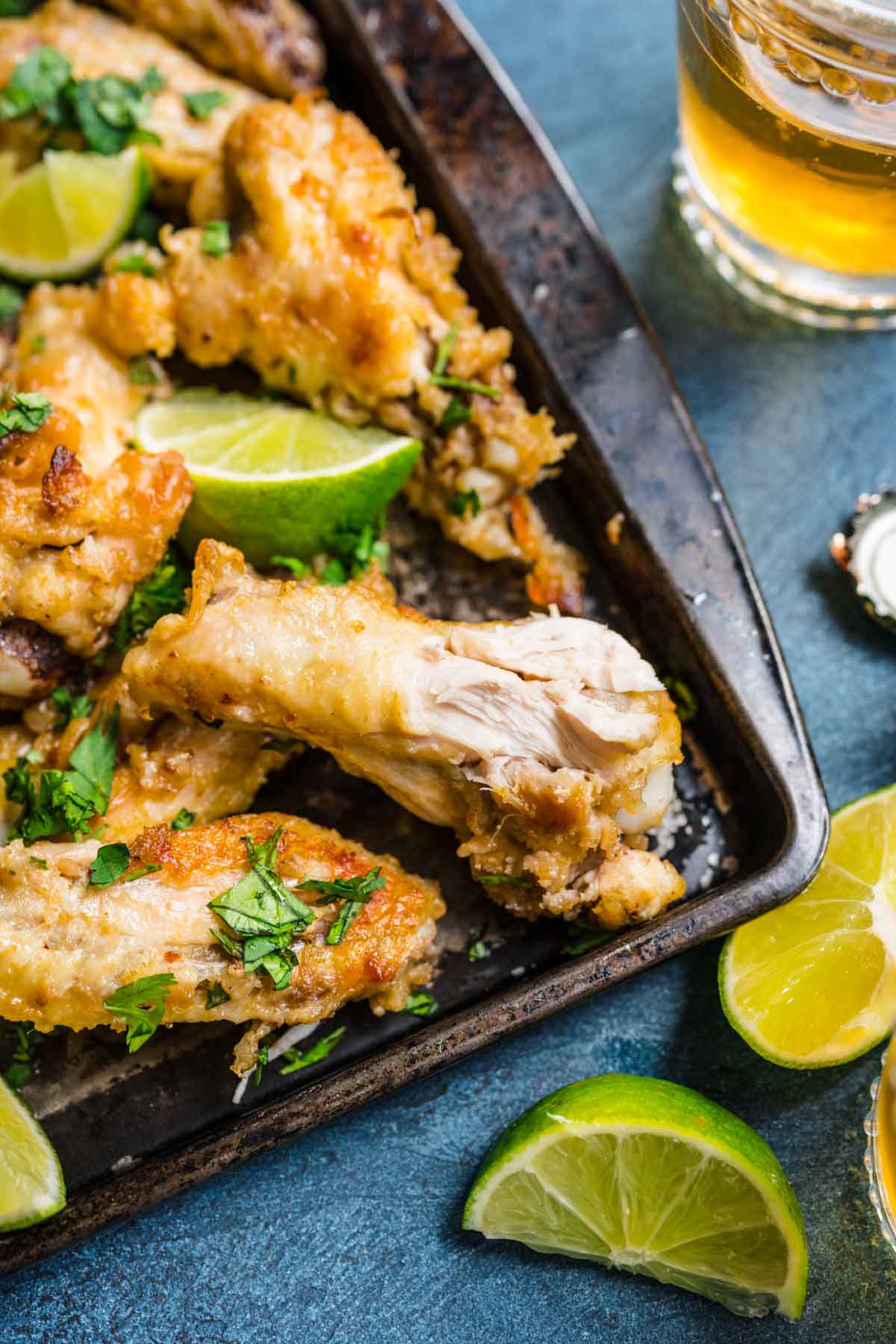 Thai Curry Chicken Wings baked on baking pan with cilantro and lime wedge garnish with bite taken