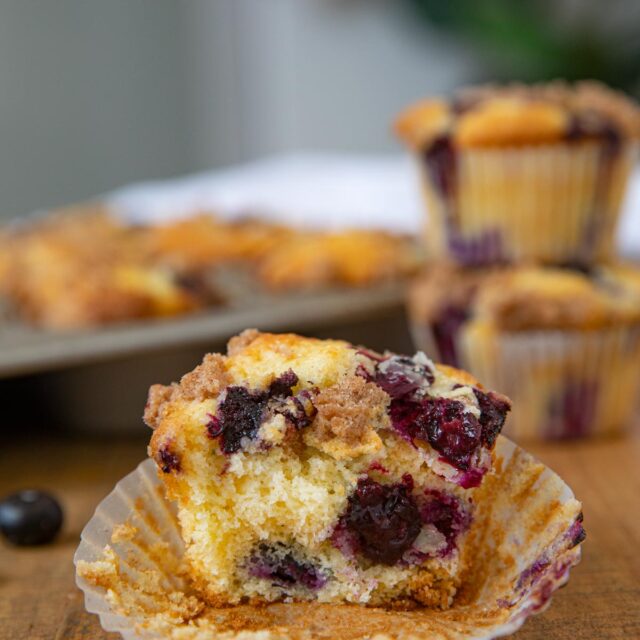 Blueberry Crumb Muffin on board with muffins behind it