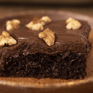 Slice of chocolate cake with frosting and walnuts