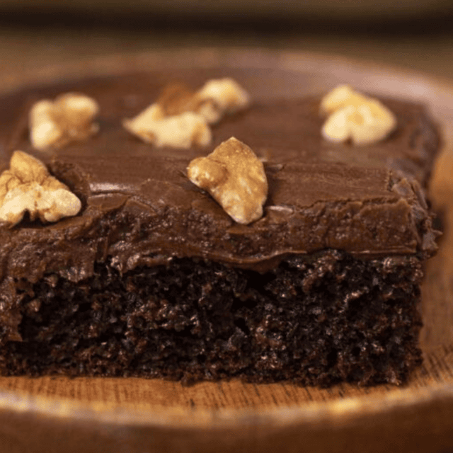 Slice of chocolate cake with frosting and walnuts