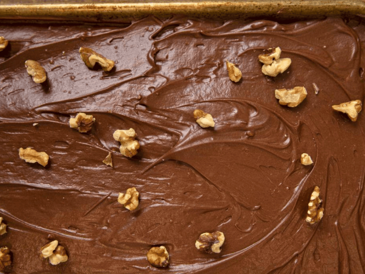 Cake on sheet pan with frosting and walnuts