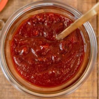 Sauce in a glass bowl with a spoon.