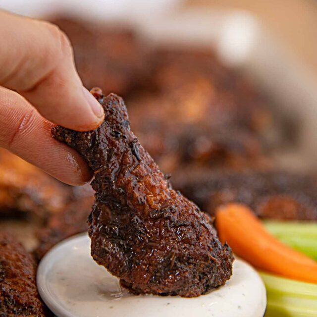 Jerk Chicken Wing being dipped into Ranch Dressing cup
