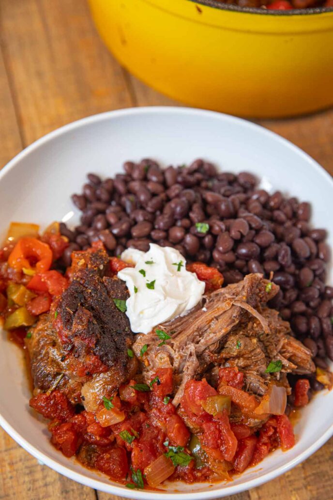 Mexican Pot Roast in bowl with black beans and sour cream