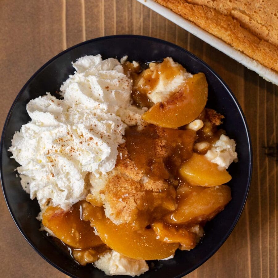 Peaches and Cream Cobbler serving in bowl with whipped cream
