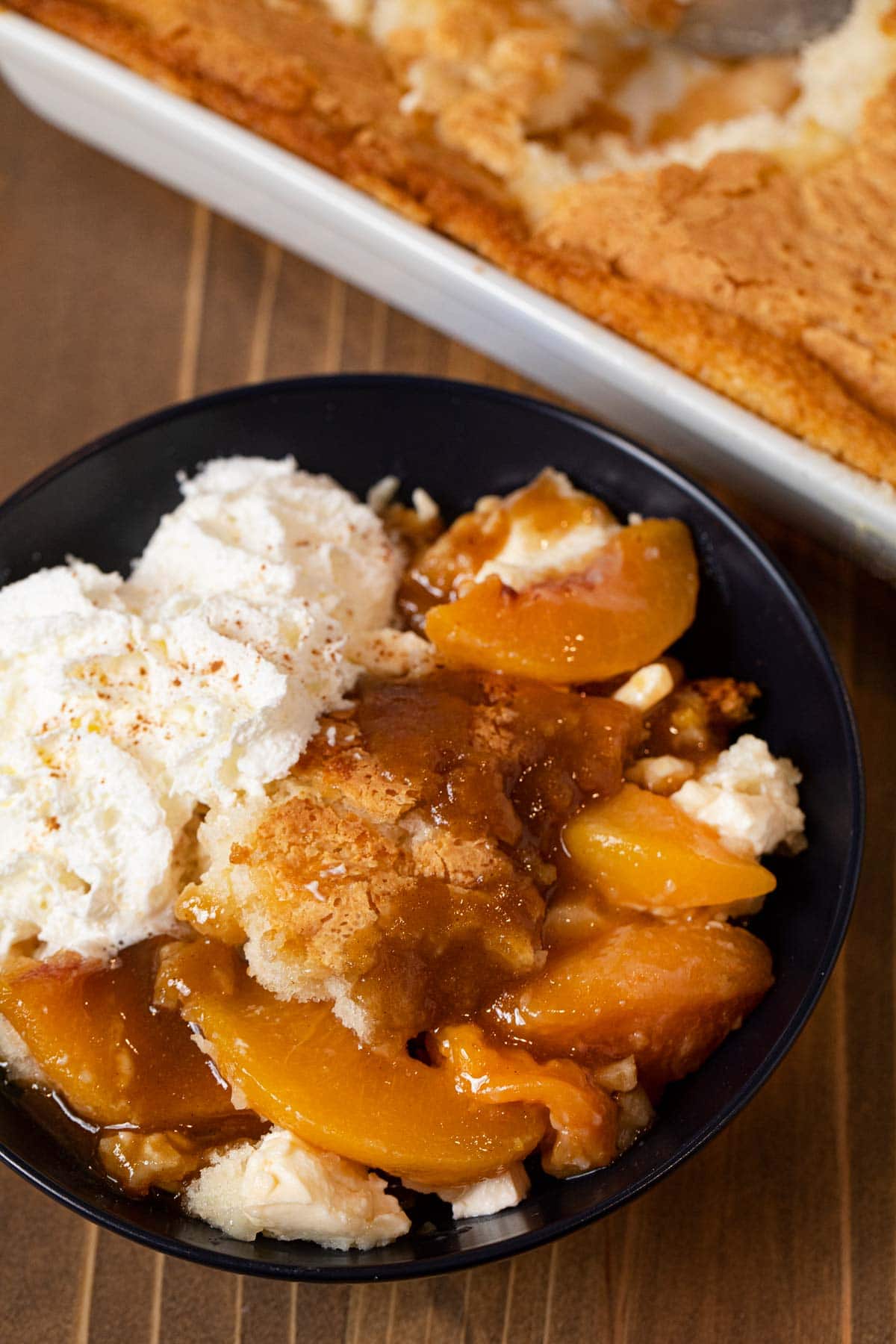 Peaches and Cream Cobbler serving in bowl with whipped cream
