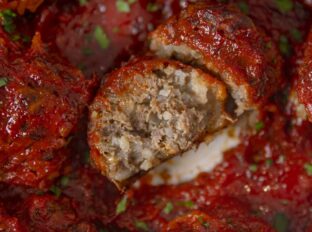 Porcupine meatball covered in marinara sauce with a bite taken out