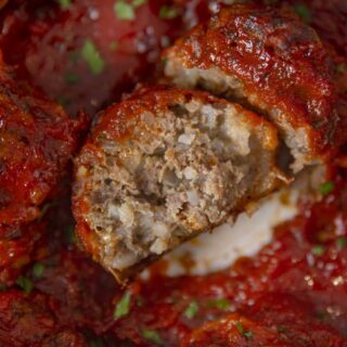Porcupine meatball covered in marinara sauce with a bite taken out