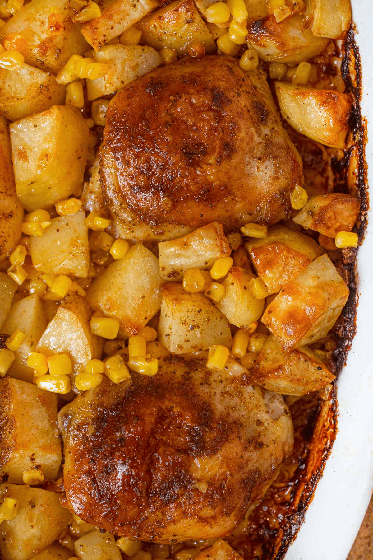 Close up of chicken, potatoes, and corn kernels in a pan