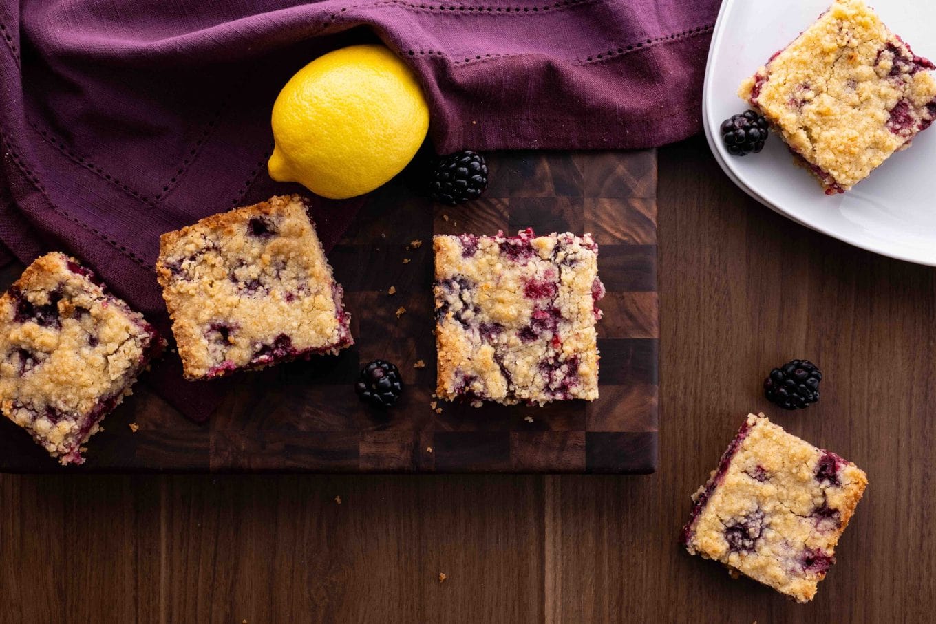 Blackberry Crumb Bars slices on board and plate with lemon and blackberries
