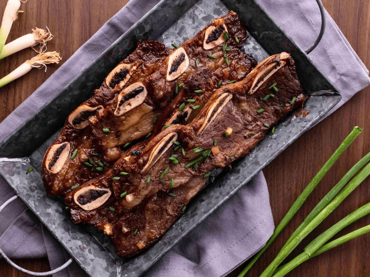 ribs on a black platter with green onion on side
