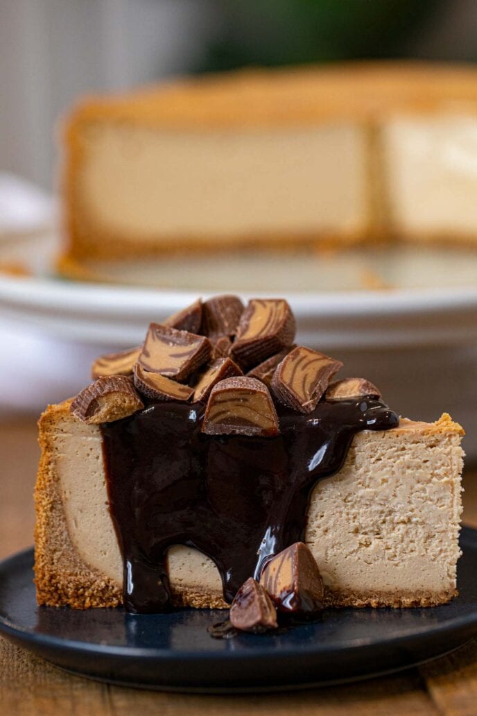 Peanut Butter Cheesecake slice on plate with chocolate sauce and peanut butter cups