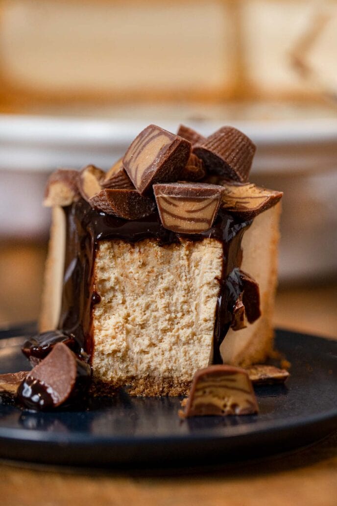 Peanut Butter Cheesecake slice on plate with chocolate sauce and peanut butter cups