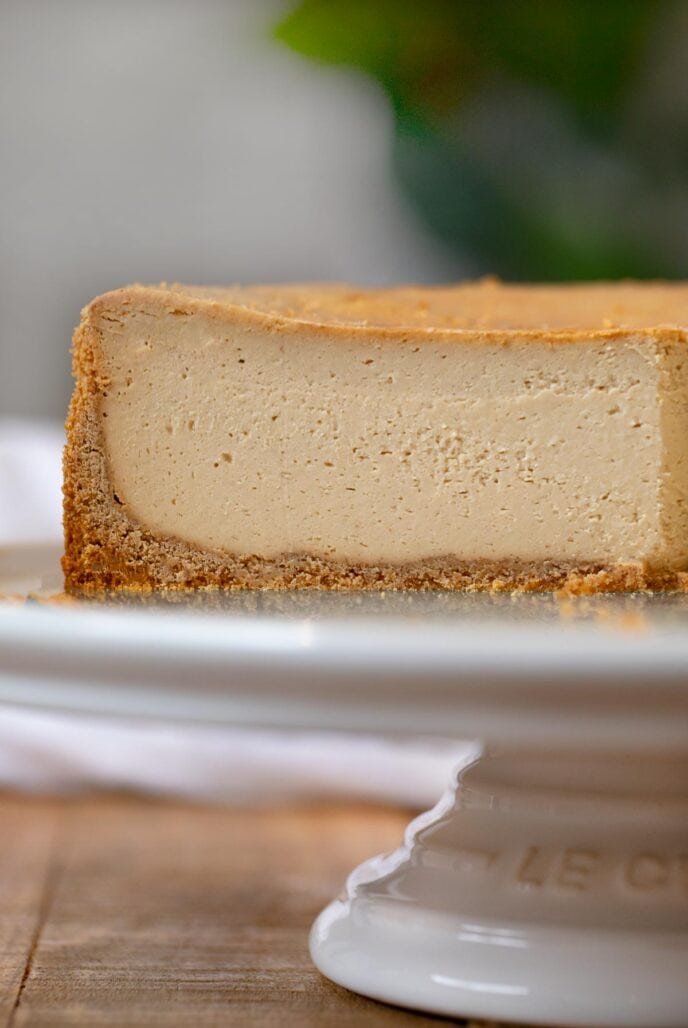 Peanut Butter Cheesecake on cake stand with slices removed