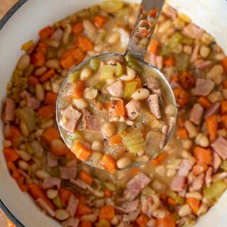 Ham and Bean Soup in ladle in large orange pot