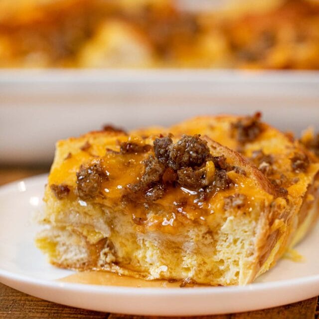 Sausage Cheddar French Toast Casserole slice on plate with maple syrup