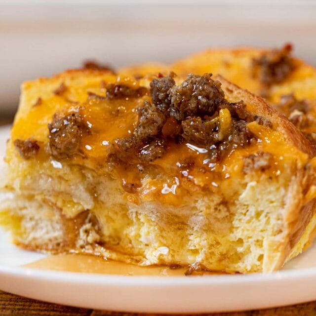 Sausage Cheddar French Toast Casserole slice on plate with maple syrup
