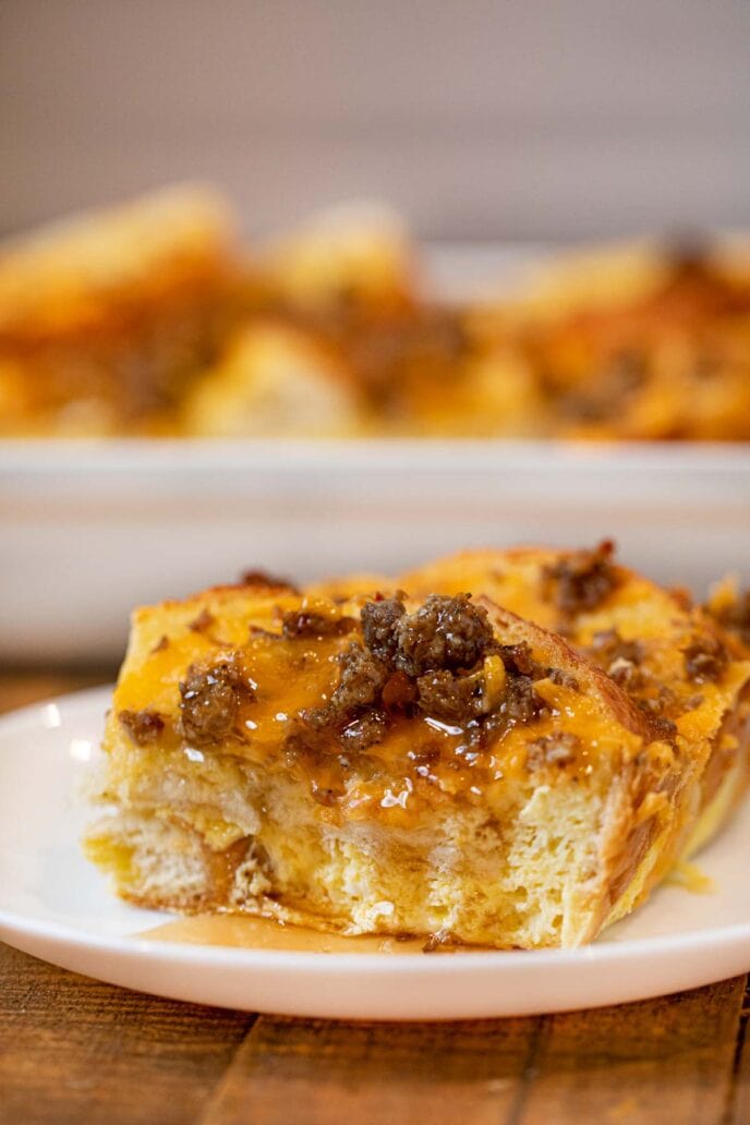 Sausage Cheddar French Toast Casserole slice on plate with maple syrup