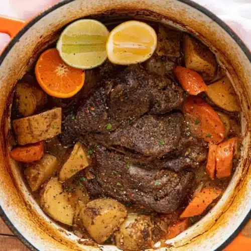 roast in pot with potatoes, carrots, lemon, lime, and orange slices