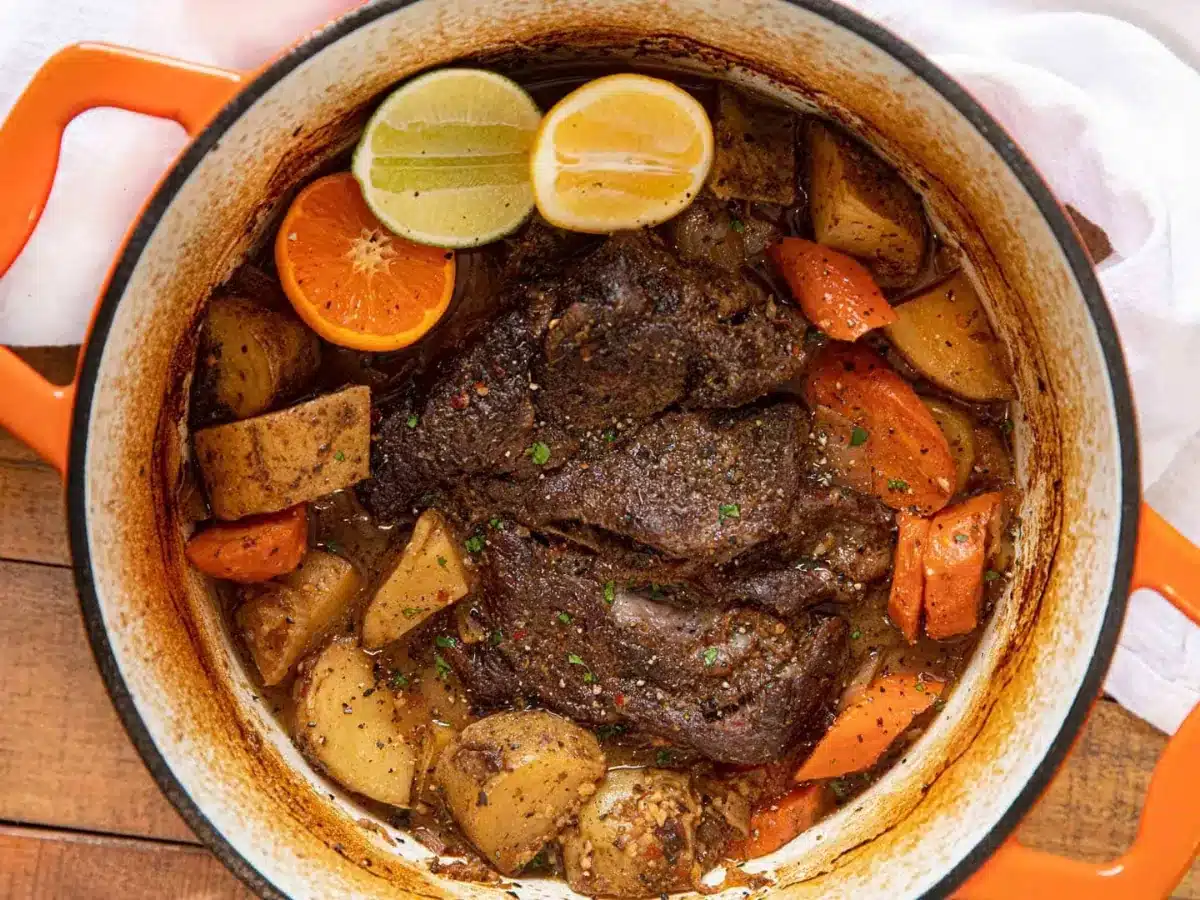 roast in pot with potatoes, carrots, lemon, lime, and orange slices