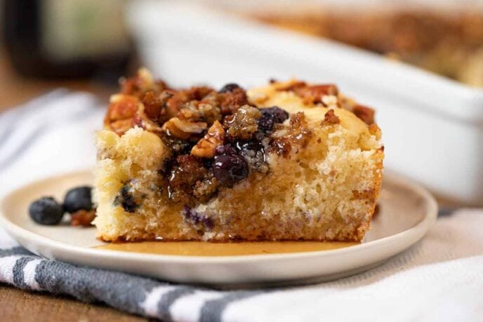 Blueberry Breakfast Casserole piece on beige plate with napkin covered in maple syrup