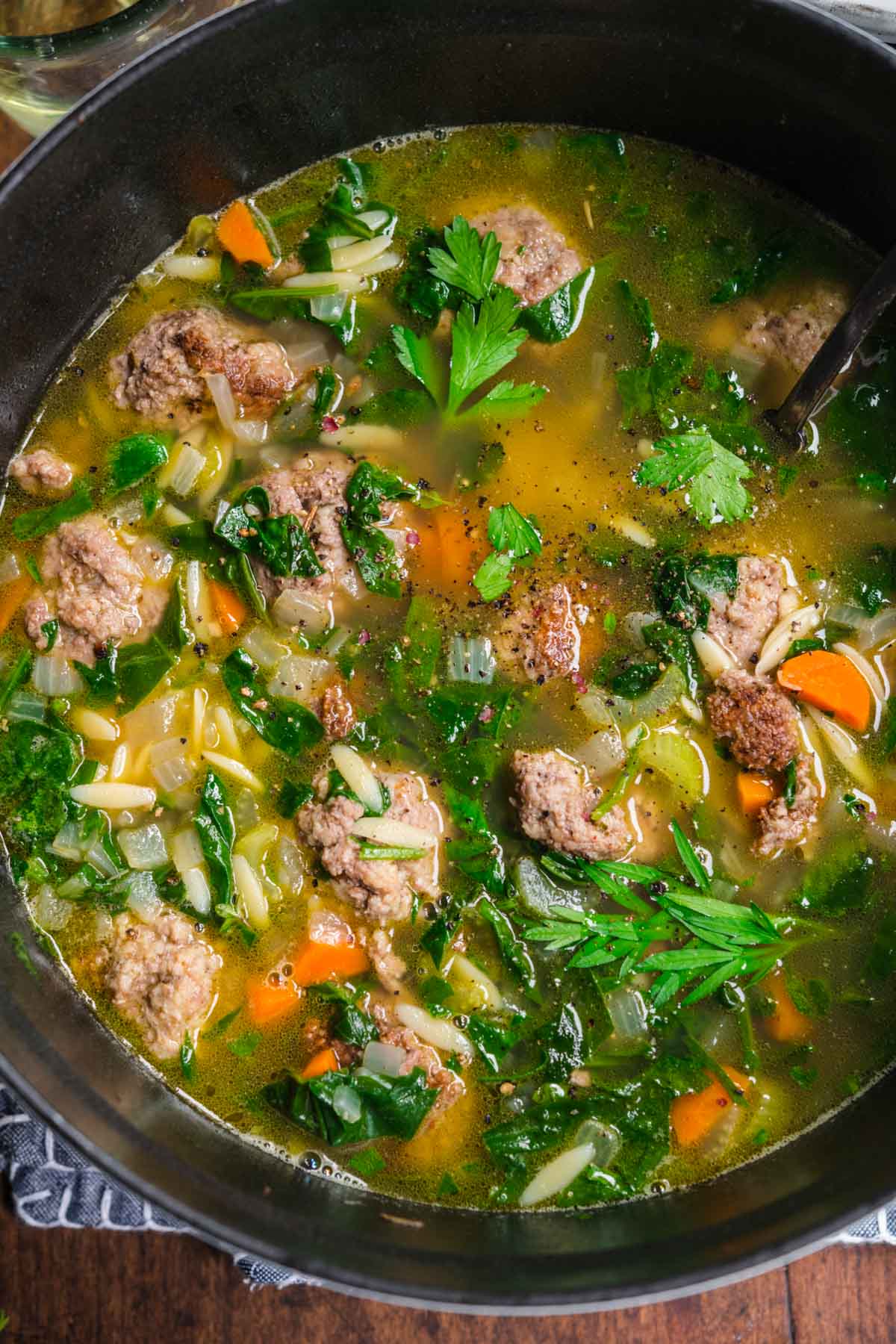 Italian Wedding Soup in pot with spoon and parsley garnish